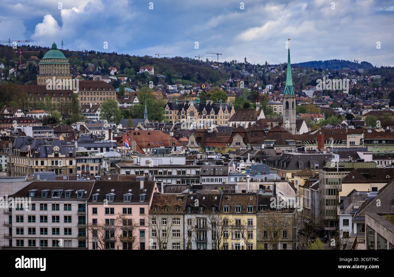 Ein Blick aus der Vogelperspektive auf die Skyline der Stadt mit ihren historischen Gebäuden, markanten Kirchtürmen und bewaldeten Hügeln unter bewölktem Himmel in Zürich, Schweiz Stockfoto