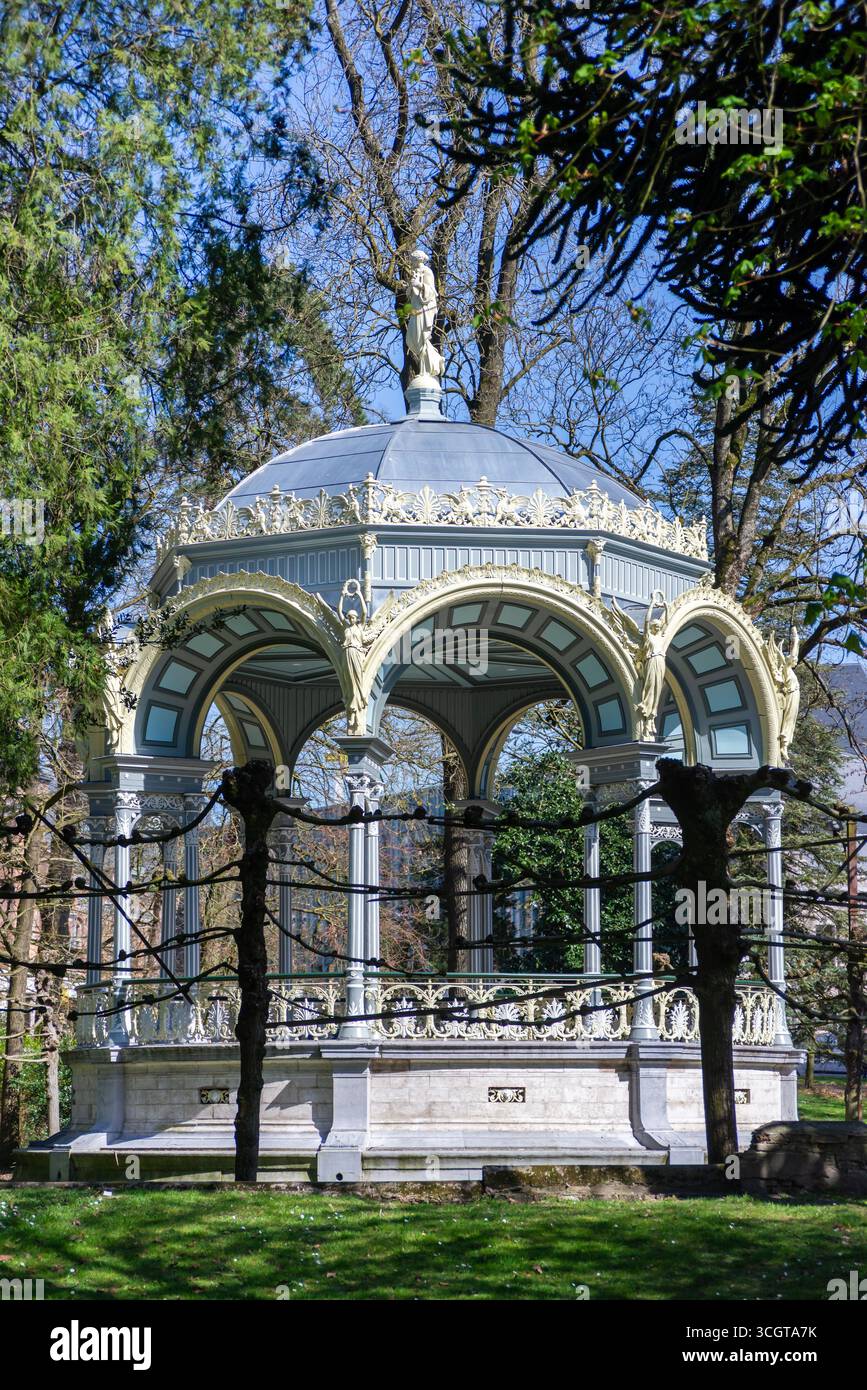 Gent, Belgien, 31.03.2025, ein eleganter Pavillon mit bogenförmigen Säulen, verzierten Details und einer Statue-gekrönten Kuppel steht in einem üppigen Park in Gent, Belgien, Stockfoto