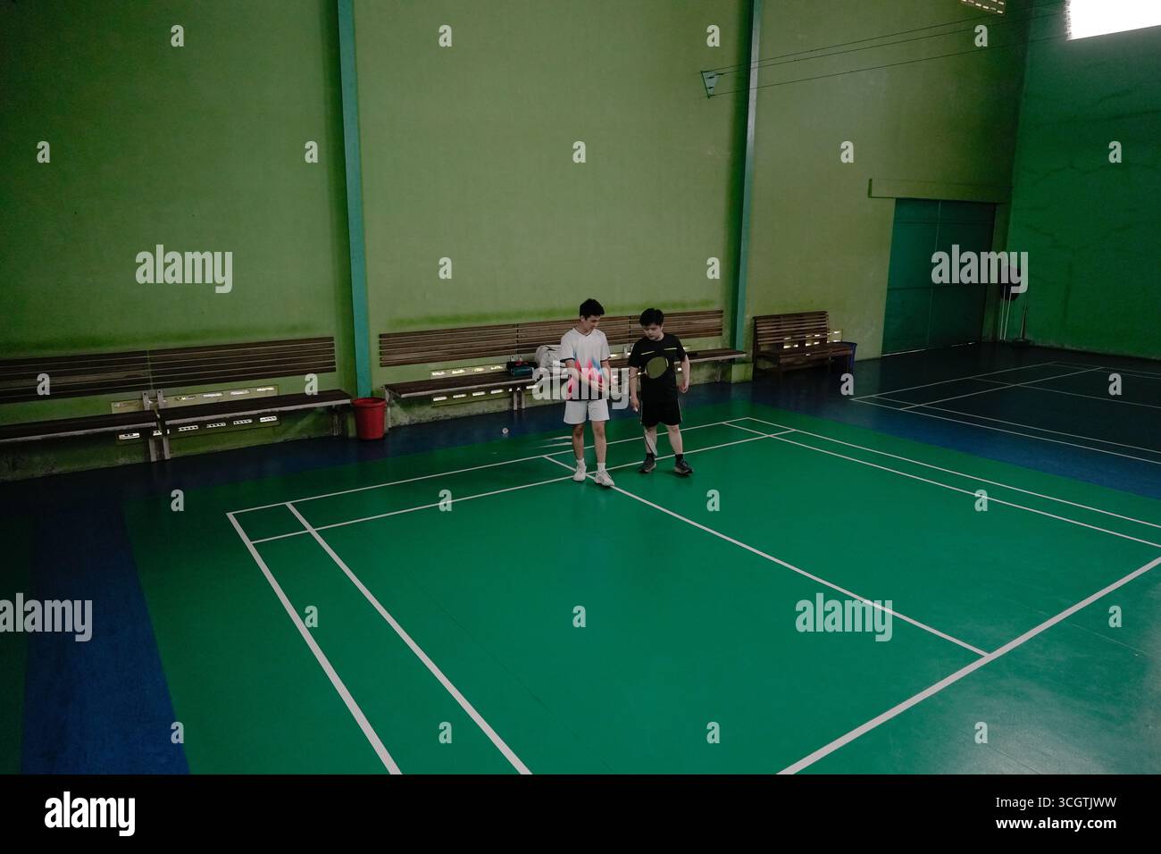 Zwei Spieler, die in einem Badmintonspiel auf einem Hallenplatz antreten Stockfoto