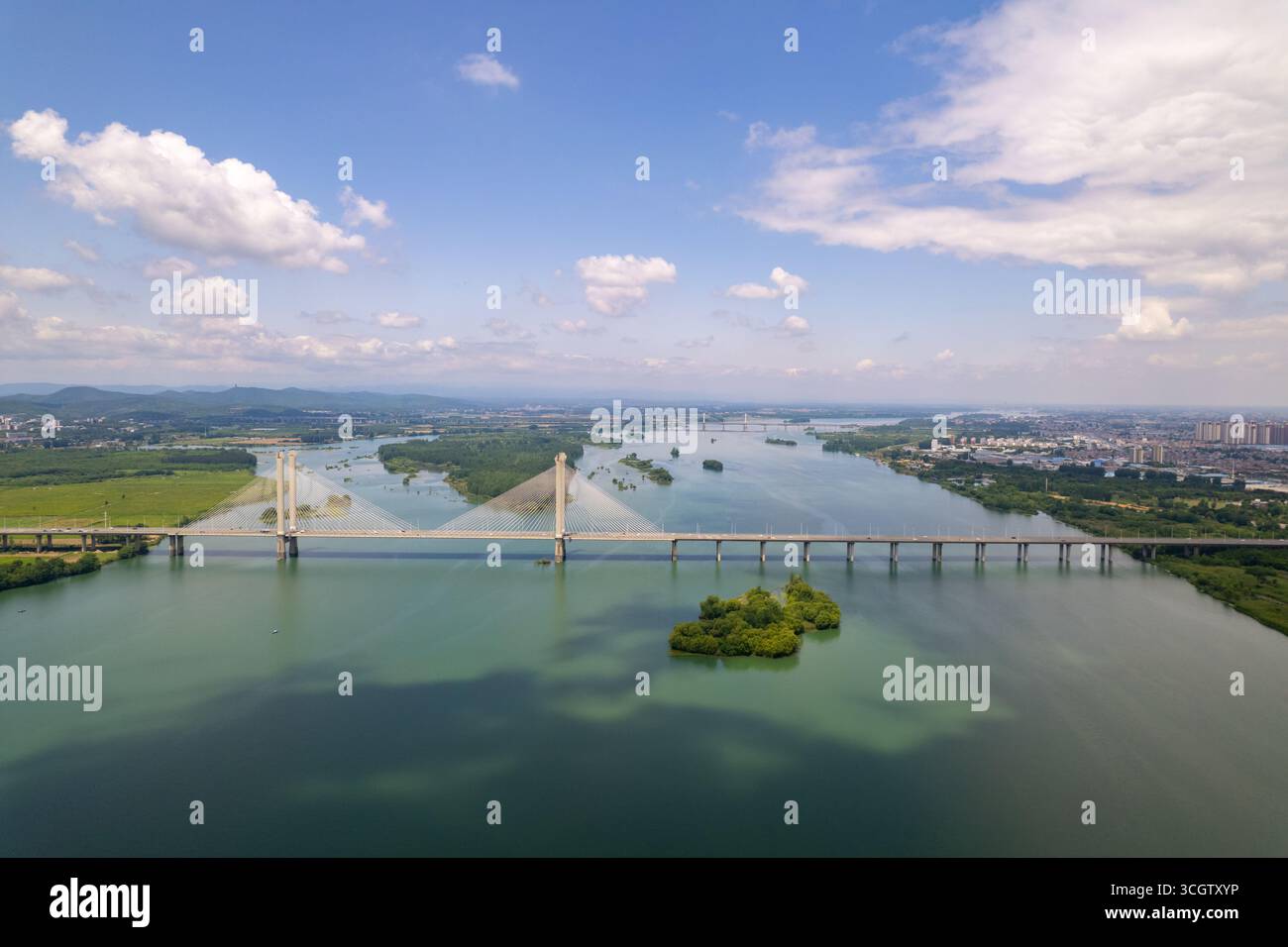 Ein Panoramablick zeigt moderne Brücken, die einen breiten Fluss mit einer Insel überqueren und sich in Richtung der Stadt Xiangyang, China, erstrecken. Stockfoto
