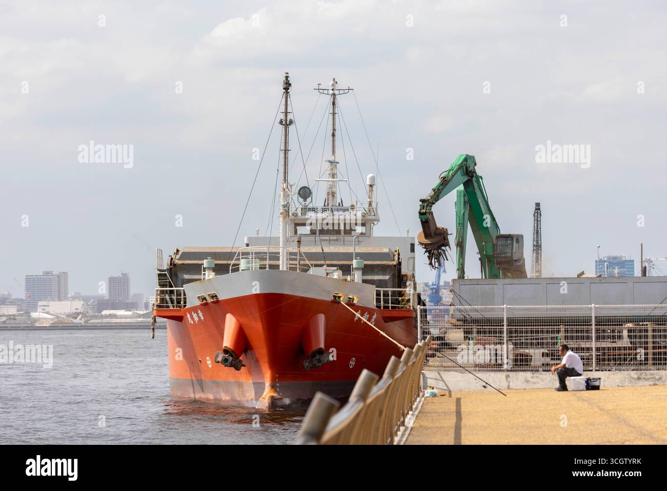 Ein Frachtschiff wird in der Bucht von Tokio mit Schrott beladen. Im Jahr 2025 haben die Zölle von Präsident Trump in der zweiten Amtszeit, darunter eine 25%ige Abgabe auf importierte Autos und Teile sowie ein "Gegenseitigkeitszoll" von 24% auf andere japanische Waren, die Japans exportgetriebene Wirtschaft erheblich unter Druck gesetzt, die für etwa 20% seiner gesamten Exporte von den USA abhängig ist (wobei allein Autos 28% davon ausmachen). Diese Maßnahmen, die im Rahmen des International Emergency Economic Powers Act erlassen wurden, führten zu unmittelbaren Auswirkungen: Japans Nikkei-Index sank im April auf 9%, die Produktion der Fabriken fiel im März um 1,1% (schlimmer als erwartet, verzögert Stockfoto