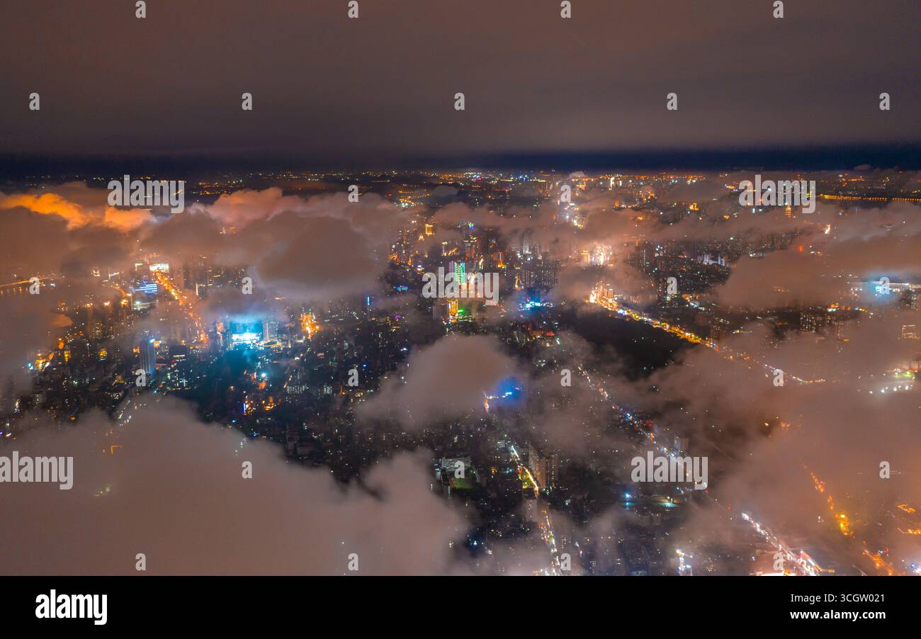 Die Lichter der Stadt Wuhan leuchten durch die niedrigen Nachtwolken und zeigen eine helle urbane Weite. Stockfoto
