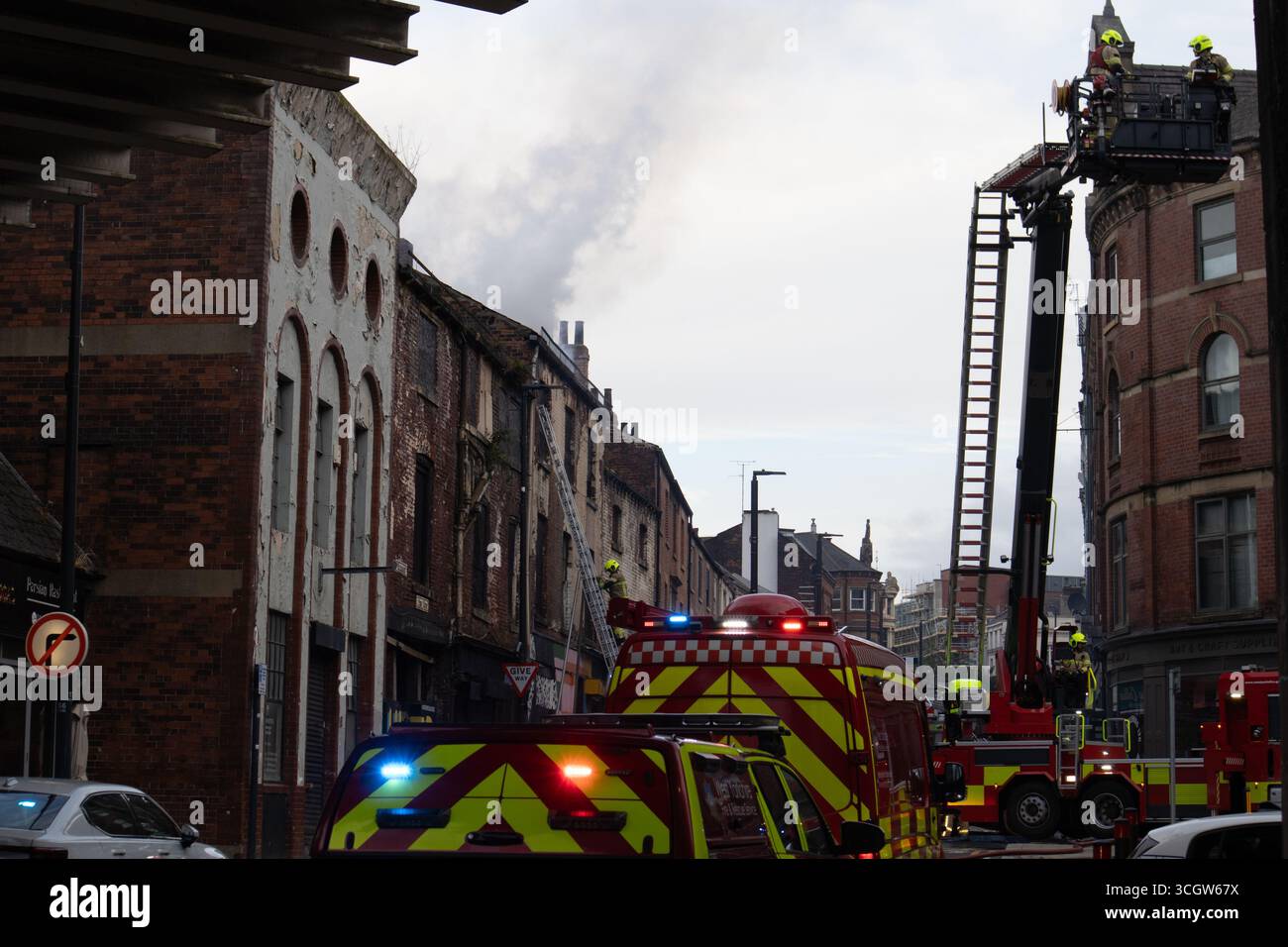 Rettungsdienst-Szene mit Feuerwehrleuten, Feuerwehrfahrzeugen und Luftplattform, die bei einem Brand in einem Stadtgebäude anwesend sind Stockfoto
