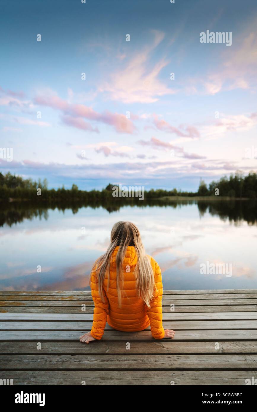 Frau, die sich an der Seebrücke entspannt, alleine in Finnland, Mädchen, das Sonnenuntergang genießt Landschaft Reise Lifestyle Outdoor Herbsturlaub Reise in die wilde Su Stockfoto