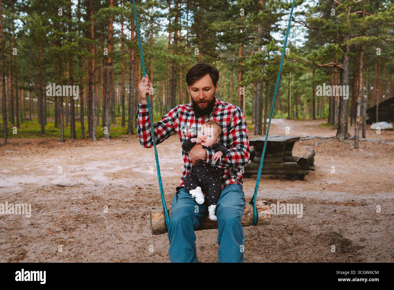 Familie Spaß Vater mit Baby schaukeln auf den Schaukeln im Wald Spielplatz Reise Urlaub Outdoor Lifestyle Sommer in Finnland, Elternvater mit Kleinkind c Stockfoto