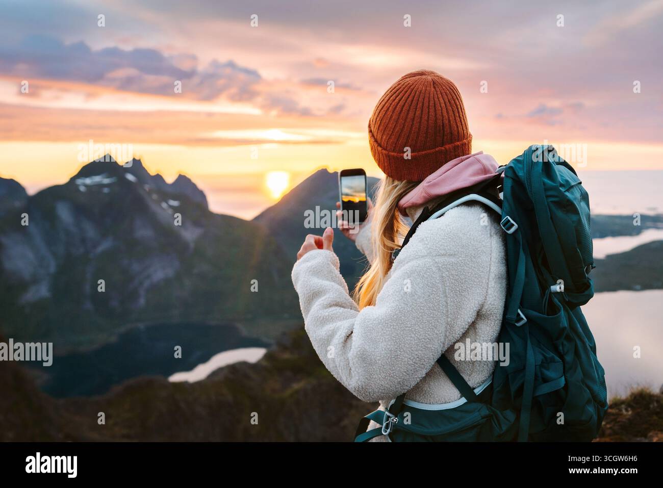 Frau Wandern in Norwegen mit Smartphone Kamera in den Bergen Reise Blogger Tourist mit Rucksack und Telefon Wandern auf den Lofoten Inseln, Aktivurlaub Stockfoto