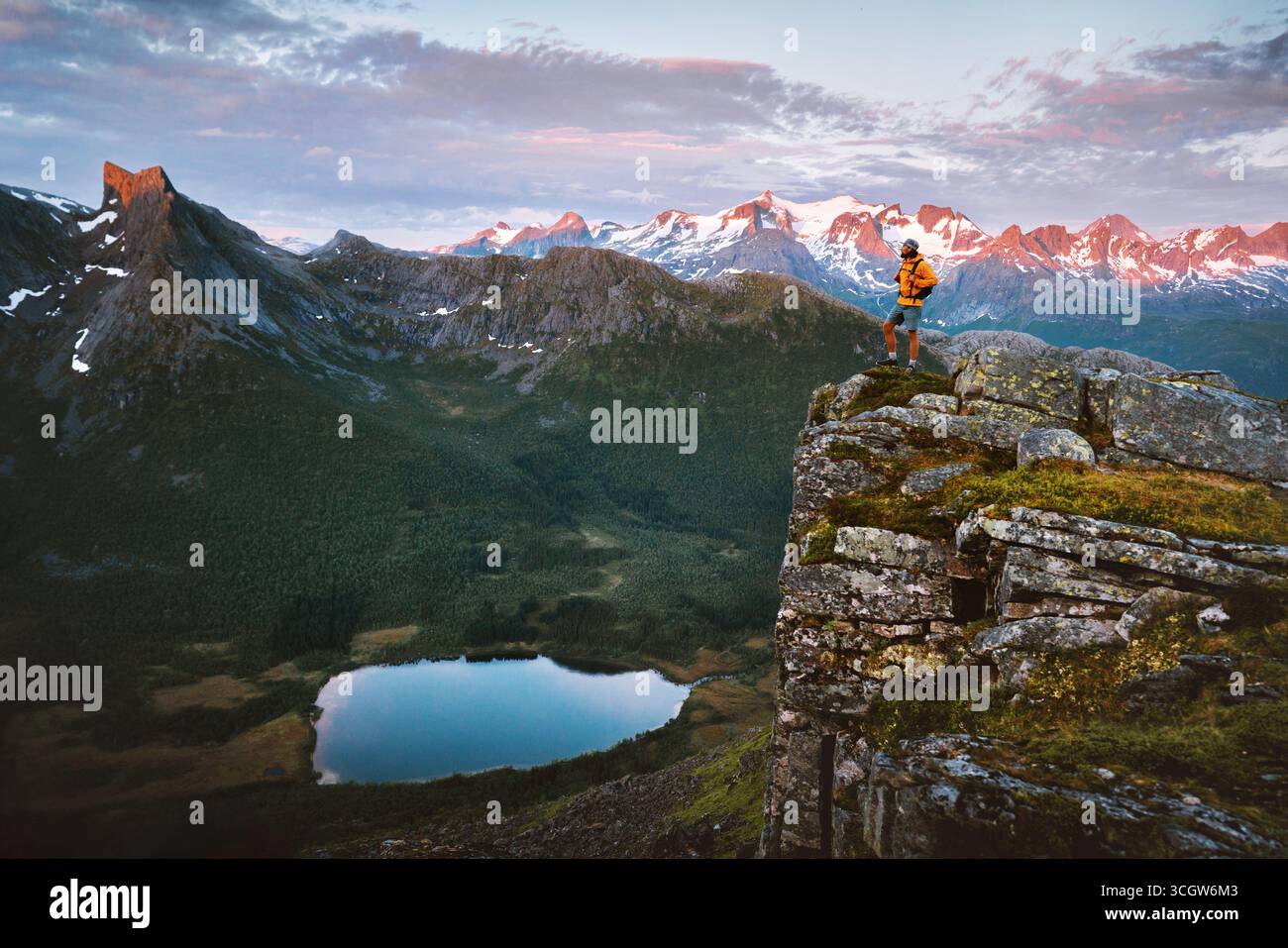 Mann, der in Norwegen unterwegs ist, auf Klippen stehend und genießt Sonnenuntergang Berge und Seeblick Reisende Wanderungen allein Aktivabenteuer extreme Urlaubstour Stockfoto