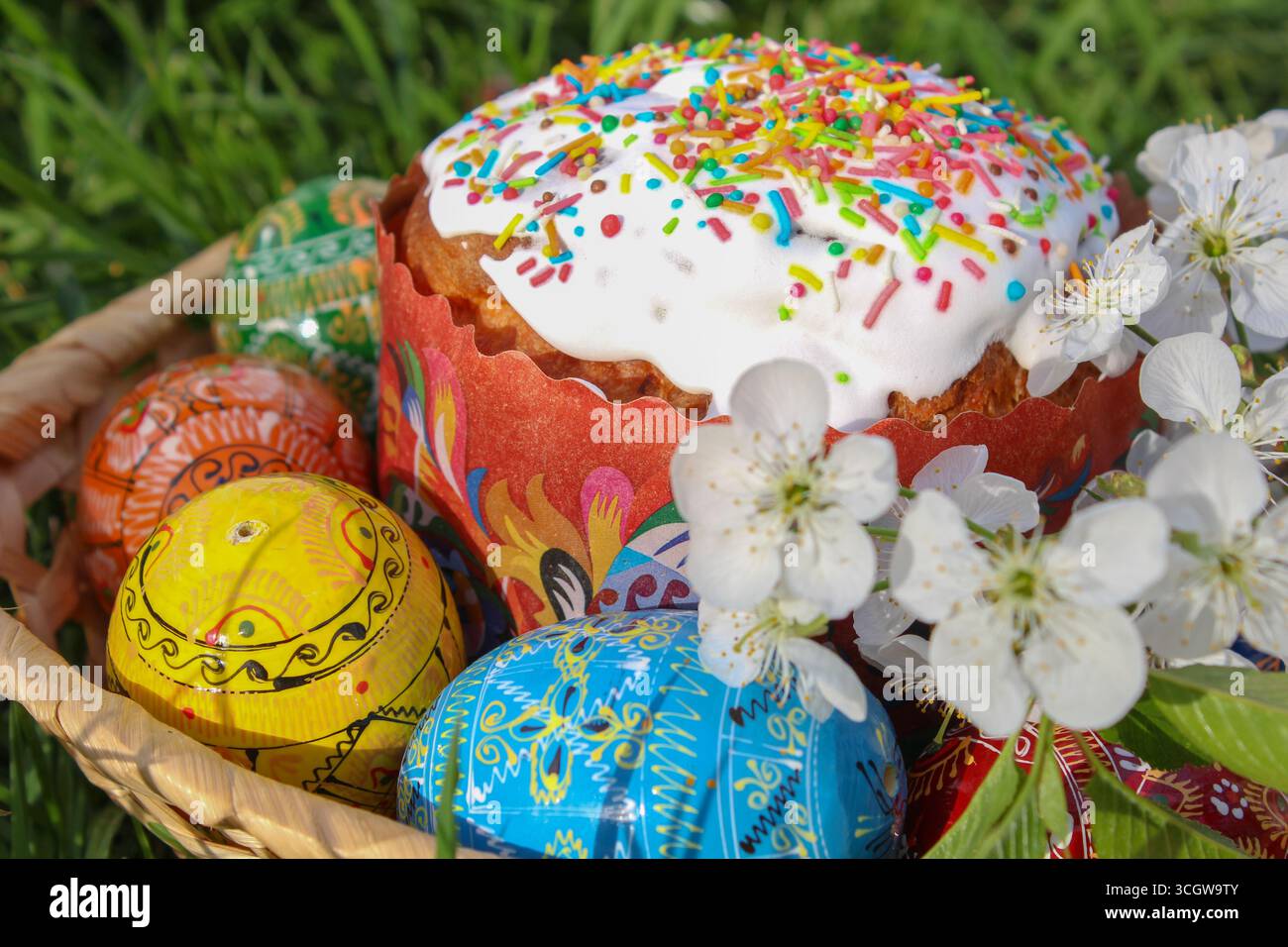 Wunderschöne ostereier mit Blumen und Kürbis im Korb auf Grashintergrund Stockfoto
