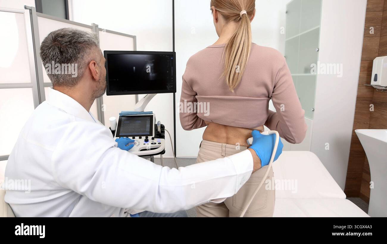 Ultraschall der Nieren. Patientin während der Ultraschalluntersuchung in der medizinischen Klinik stehend, Rücksicht, Nahaufnahme Stockfoto