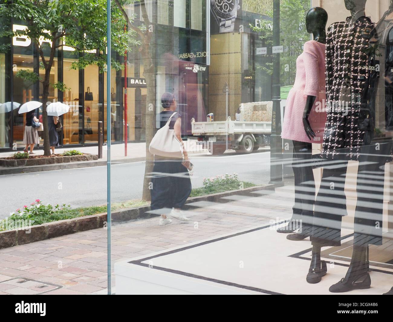 TOKIO, JAPAN - 29. August 2025: Blick auf Tokios Ginza-Viertel mit einer Ausstellung im Fenster eines Chanel-Geschäfts. Ein Bally-Laden ist gegenüber. Stockfoto