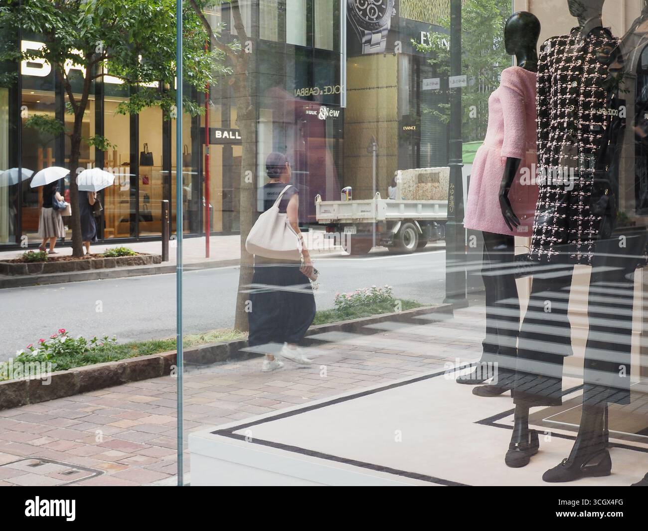 TOKIO, JAPAN - 29. August 2025: Blick auf Tokios Ginza-Viertel mit einer Ausstellung im Fenster eines Chanel-Geschäfts. Ein Bally-Laden ist gegenüber. Stockfoto