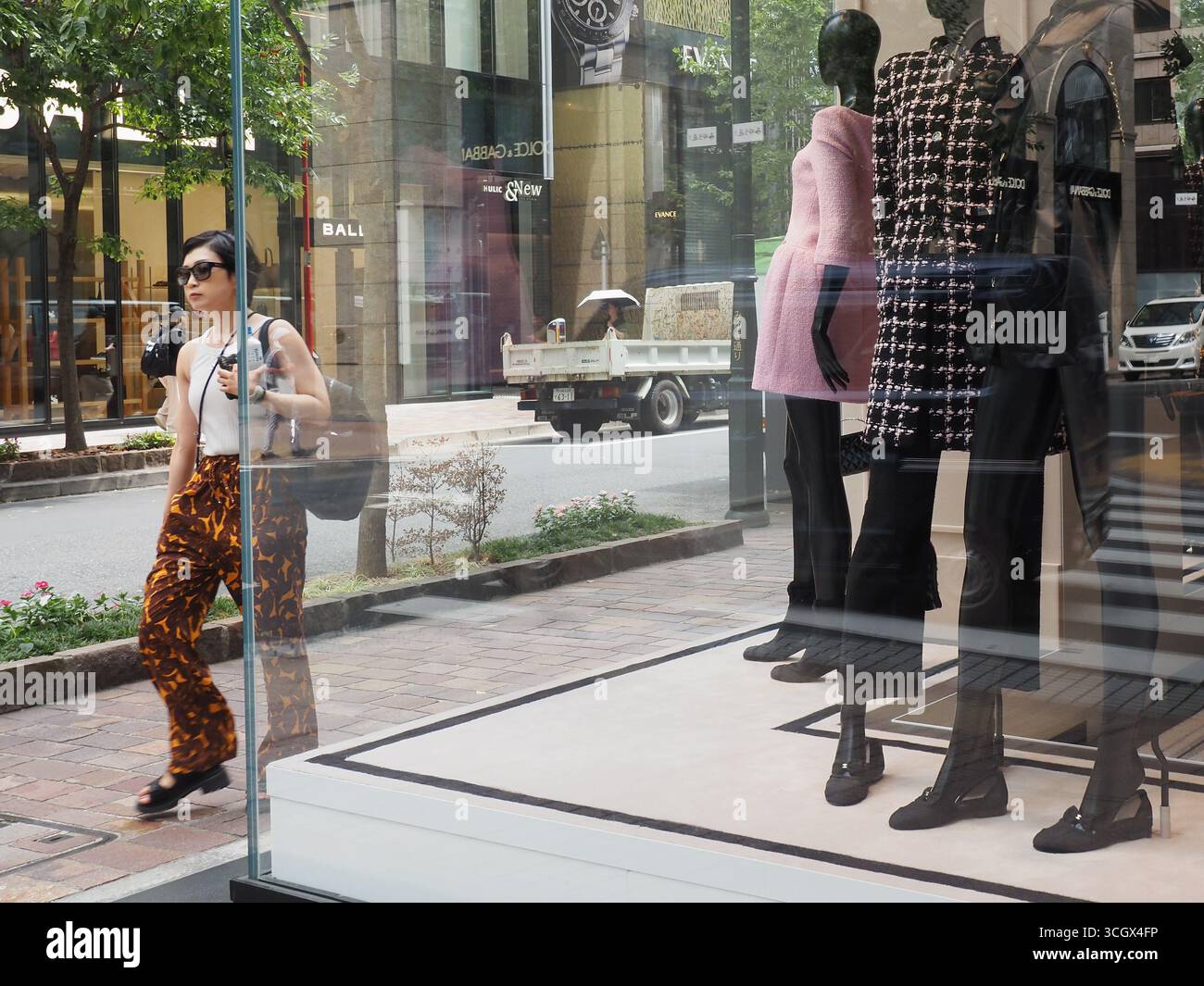 TOKIO, JAPAN - 29. August 2025: Blick auf Tokios Ginza-Viertel mit einer Ausstellung im Fenster eines Chanel-Geschäfts. Ein Bally-Laden ist gegenüber. Stockfoto