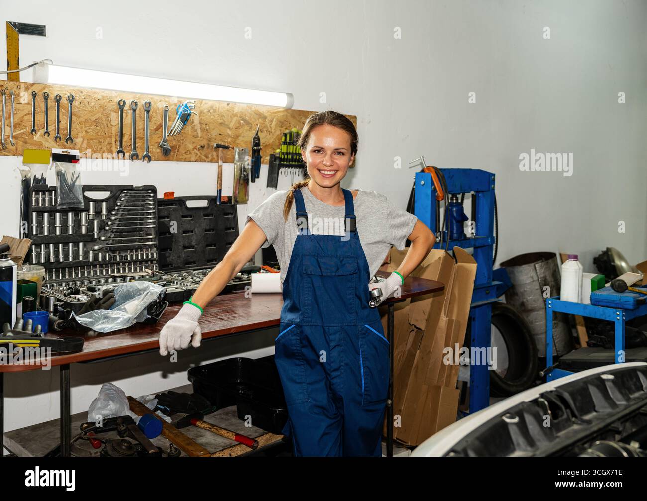 Porträt einer fröhlichen Mechanikerin in Arbeitsuniform in der Werkstatt Stockfoto