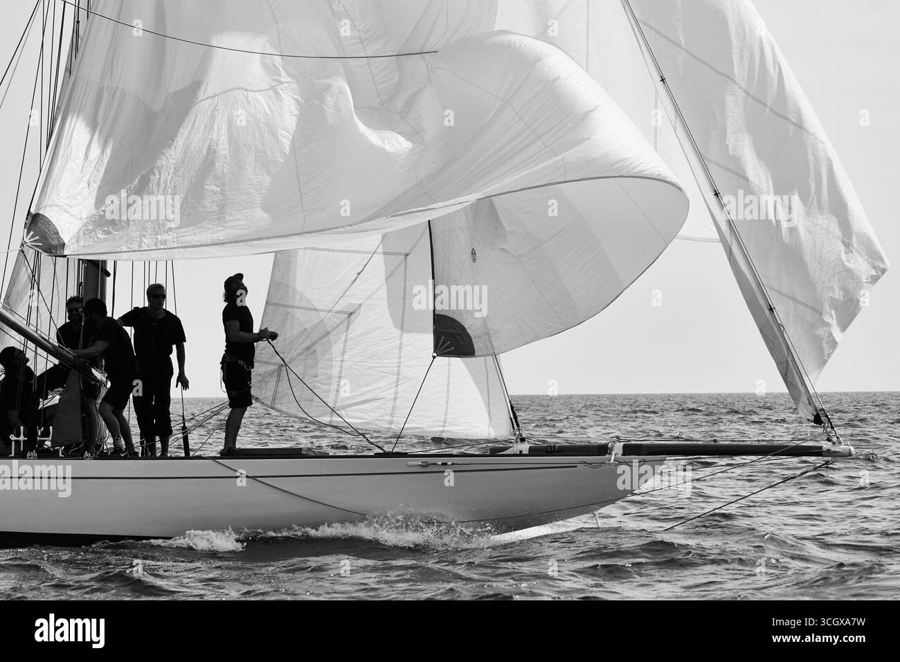 Schwarz-weiß-Segelszene mit Besatzung, die die Segel während einer klassischen Yacht Regatta justiert. Stockfoto