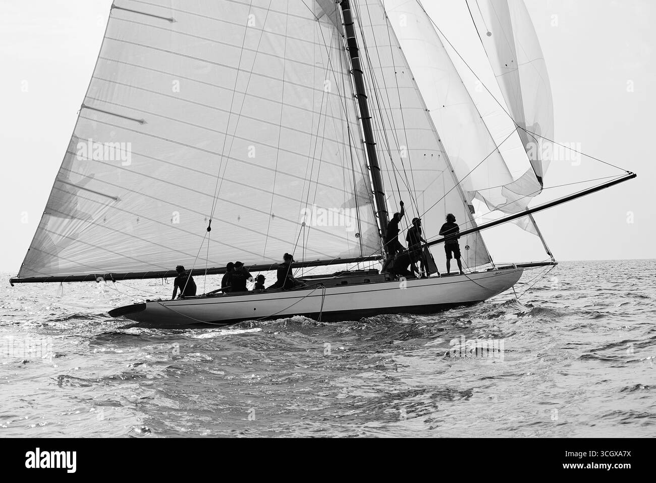 Schwarz-weiß-Segelszene mit Besatzung, die die Segel während einer klassischen Yacht Regatta justiert. Stockfoto