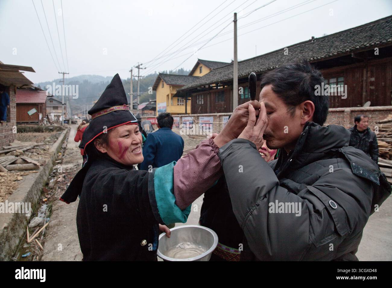 Die Miao Tante gab dem Maio-Onkel Alkohol, der das Spiel im Kongsheng Miao Nationalitätendorf verlor. Stockfoto