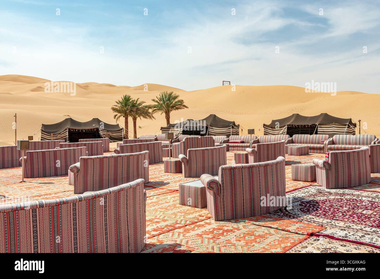 VAE - Liwa - Majlis and Dunes Panorama - Teppiche und Sofas mit Blick auf schwarze Zelte unter weichem Wüstenlicht Stockfoto