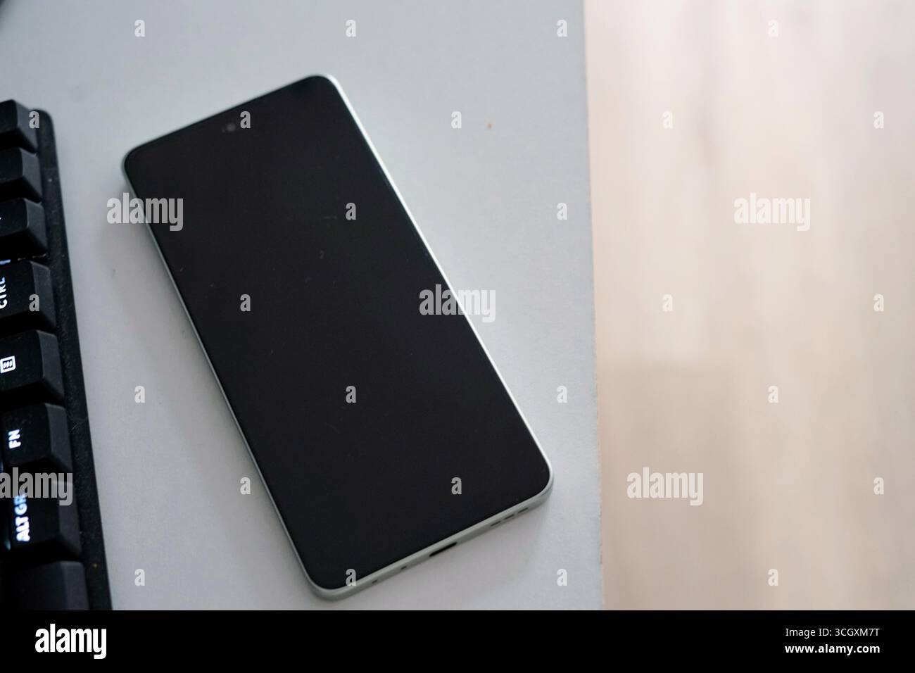 Ein schlankes Smartphone liegt auf einem minimalistischen Schreibtisch und zeigt sein elegantes Design. Perfekt für Technik- und Lifestyle-Bilder. Stockfoto