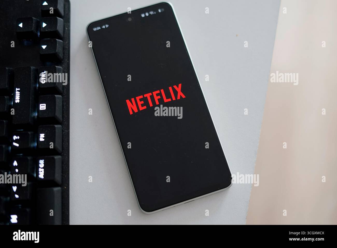 Ein modernes Smartphone mit dem Netflix App-Symbol auf einer eleganten Schreibtischoberfläche. Perfekt zur Darstellung mobiler Unterhaltungskonzepte und digitaler VI Stockfoto