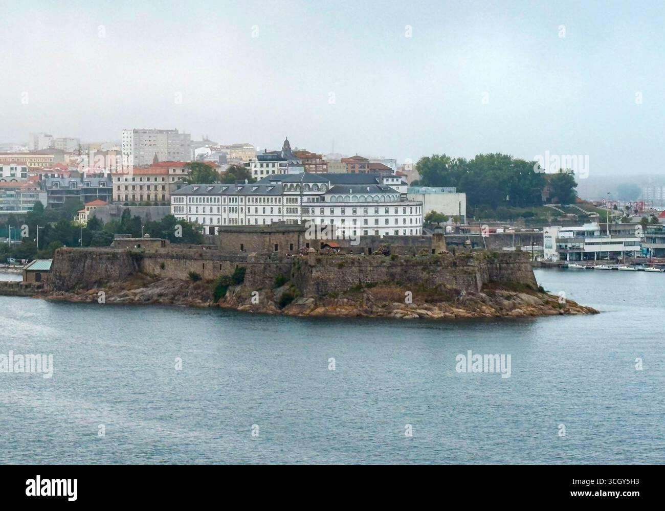 Die felsige Insel beherbergt eine alte Festung, umgeben von ruhigem Wasser in einer Küstenstadt in Spanien. Stockfoto