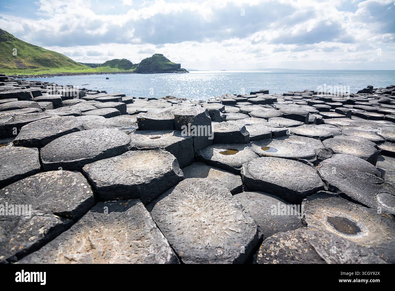 Sechseckige Basaltsäulen am Giants Causeway in Nordirland mit Sonnenschein, die an die Legende eines Riesen-Damms zwischen Irland und Schottland erinnern Stockfoto