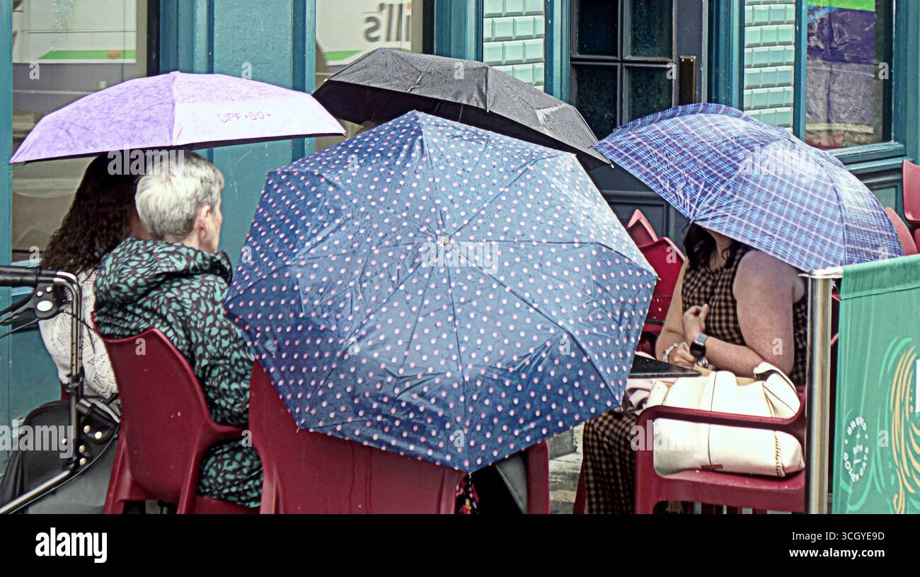 Glasgow, Schottland, Großbritannien. 30. August 2025. Wetter in Großbritannien: Der Sommer verschwand, als starker Regen die Hitzewelle im Stadtzentrum ablöste. Die Damen strömen und stellen sich in die Warteschlange für die Bay City Rollers Musical „Rollers Forever“ im Pavillon Theater. Credit Gerard Ferry/Alamy Live News Stockfoto