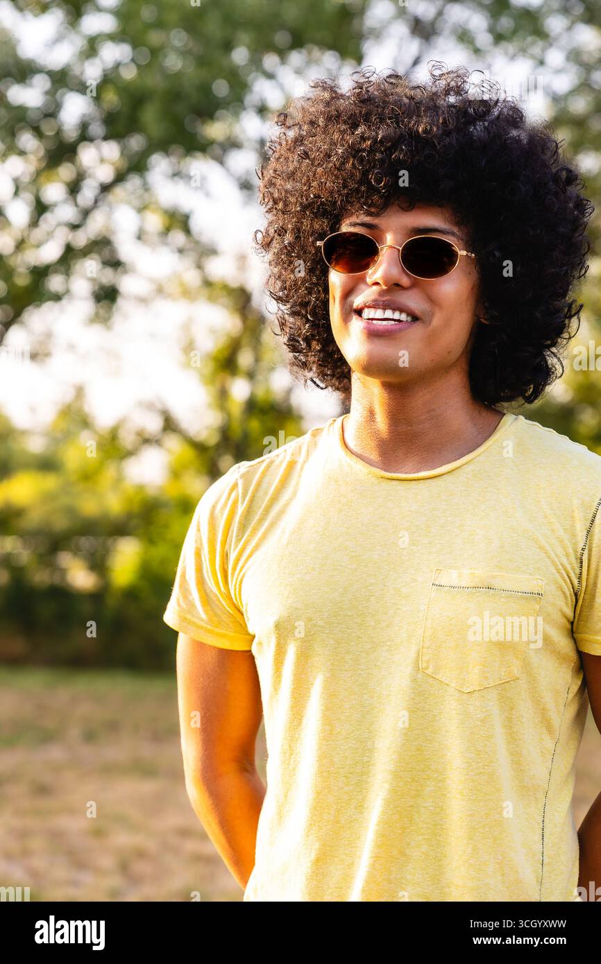 Junger Mann mit Sonnenbrille und Afro-Frisur, der den Sommer im Park genießt Stockfoto