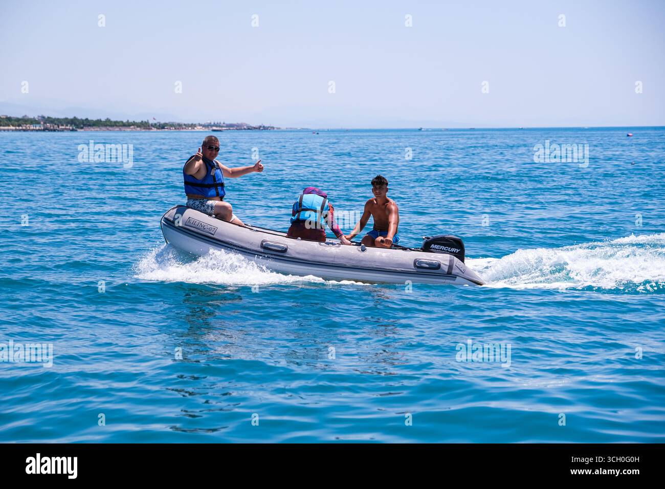 belek, Turkiye, 27.07.2025 Mann und junger Mann auf einem Schnellboot, der die Daumen hochlegt. Sommerurlaub und Abenteuer am Meer. Aktive Freizeit- und Wassersport-Aktivitäten Stockfoto