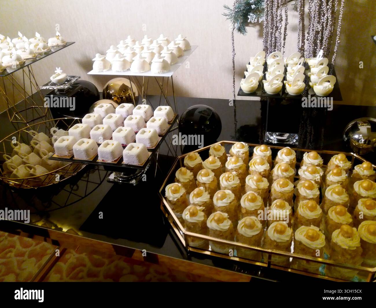 Herrlicher süßer Tisch mit verschiedenen festlichen Köstlichkeiten wie Cupcakes, Keksen und Gebäck während der Weihnachtszeit Stockfoto