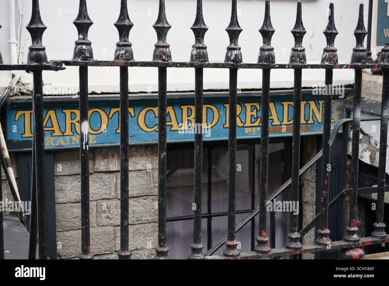Das Schild für ein „Tarot Card Reading“-Geschäft ist hinter einem schwarzen Metallgeländer auf einer Stadtstraße zu sehen. Stockfoto