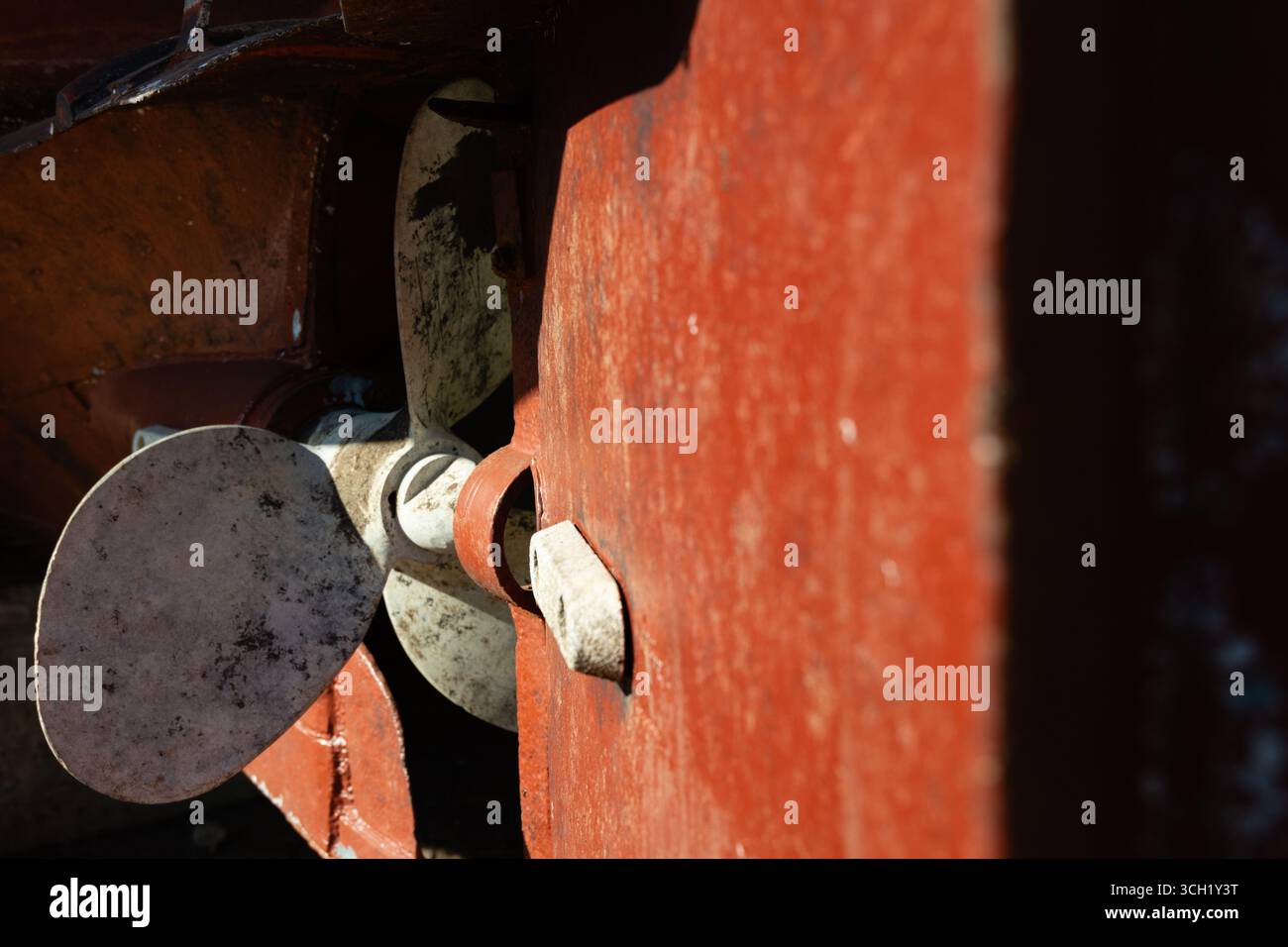 Rostiger, weiß lackierter Propeller auf einem alten roten Schiff im Trockendock. Stockfoto