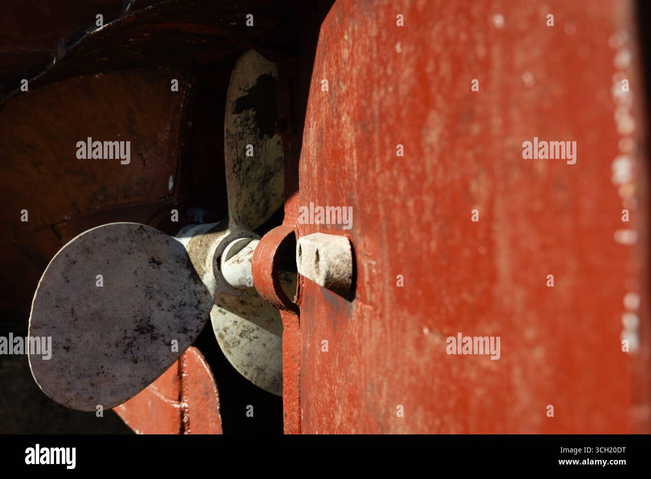 Rostiger, weiß lackierter Propeller auf einem alten roten Schiff im Trockendock. Stockfoto