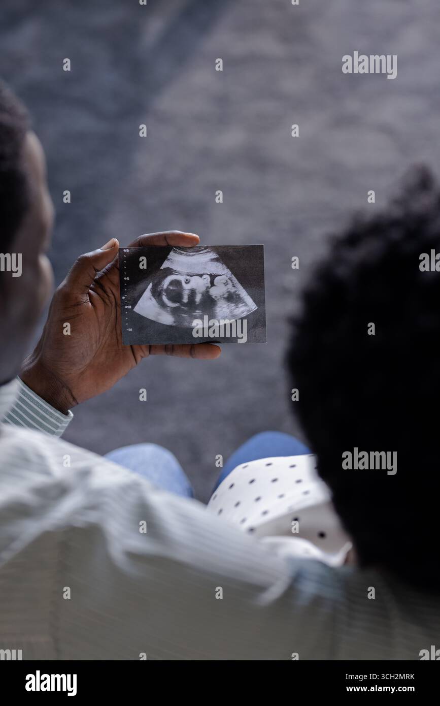 Das Afroamerikanerpaar hält ein Ultraschallbild und erwartet freudig ein neues Familienmitglied Stockfoto