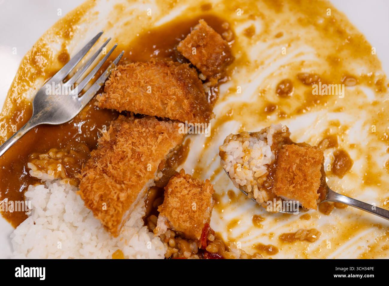 Ein japanisches Curry mit Schweinekotelett, das beim Verzehr realistisch und unarrangiert präsentiert wird. Stockfoto