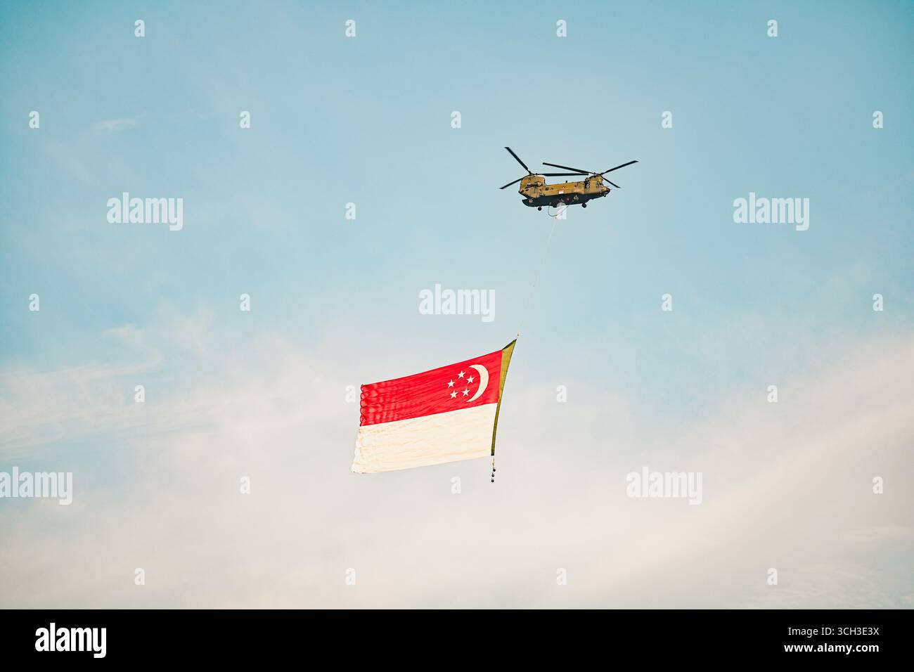 Militär-Chinook-Hubschrauber mit Singapur-Flagge während der Luftführung gegen blauen Himmel - patriotisches Verteidigungskonzept für die Feier des Nationalfeiertags Stockfoto