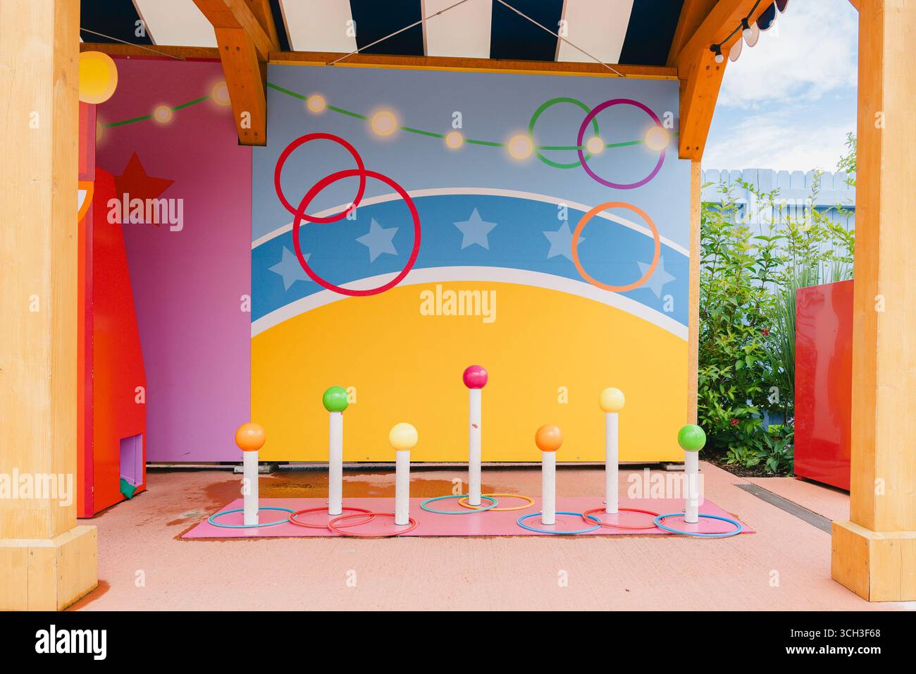 Farbenfrohe Ringwerfen in einer verspielten Umgebung im Freien mit lebhaften Stangen und einer fröhlichen Kulisse. Perfekt für Familienspaß, Karnevalsveranstaltungen oder Stockfoto