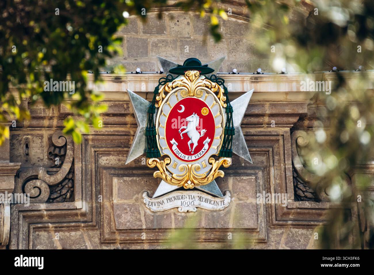 Birgu, Malta – 11. April 2025: Verziertes Wappenemblem mit weißem Pferd, Mondsichel, Goldblume und lateinischem Motto „Fidelis et Verax“ Stockfoto