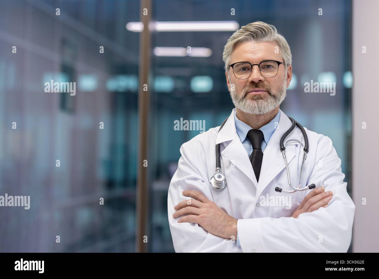 Erfahrener männlicher Arzt in professioneller Kleidung, der selbstbewusst in einer modernen Gesundheitseinrichtung steht. Stockfoto