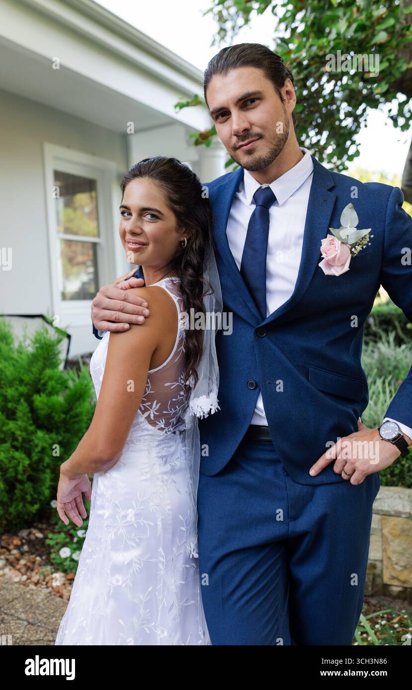 Braut und Bräutigam lächeln im Freien und tragen elegante Hochzeitskleidung Stockfoto