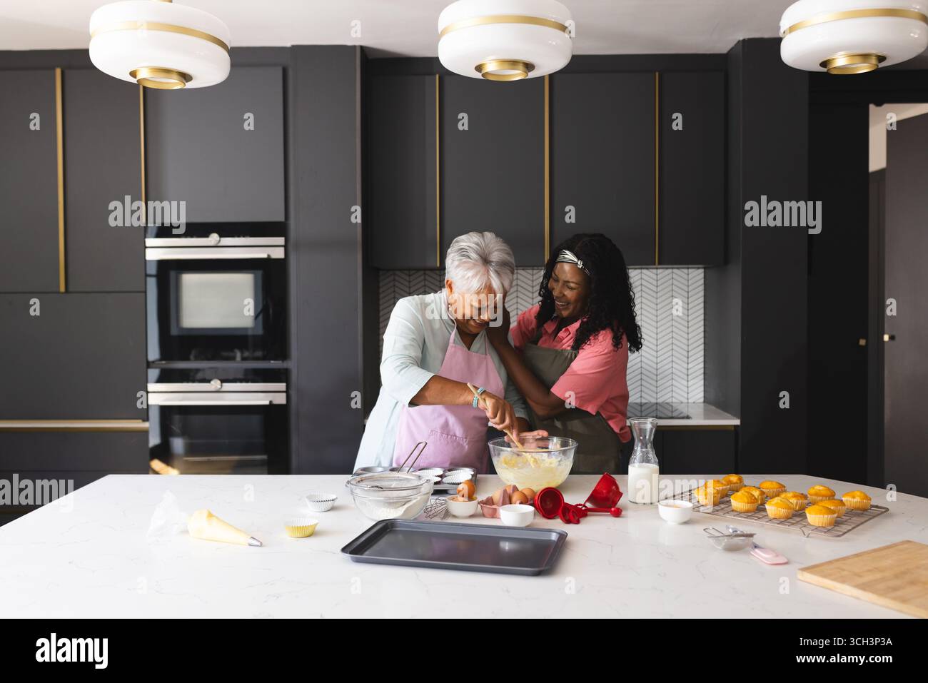 Backen in der Küche, Seniorenmutter und Erwachsene Tochter teilen einen freudigen Moment, zu Hause Stockfoto