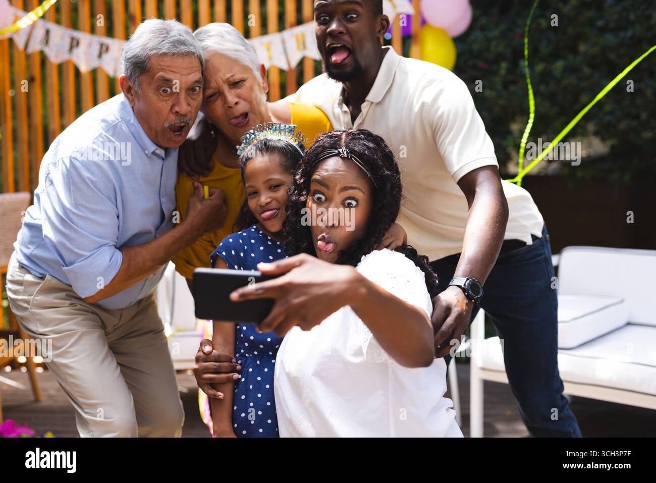 Auf der Party macht die Familie lustige Gesichter, während sie Selfie auf der Geburtstagsparty im Garten macht Stockfoto