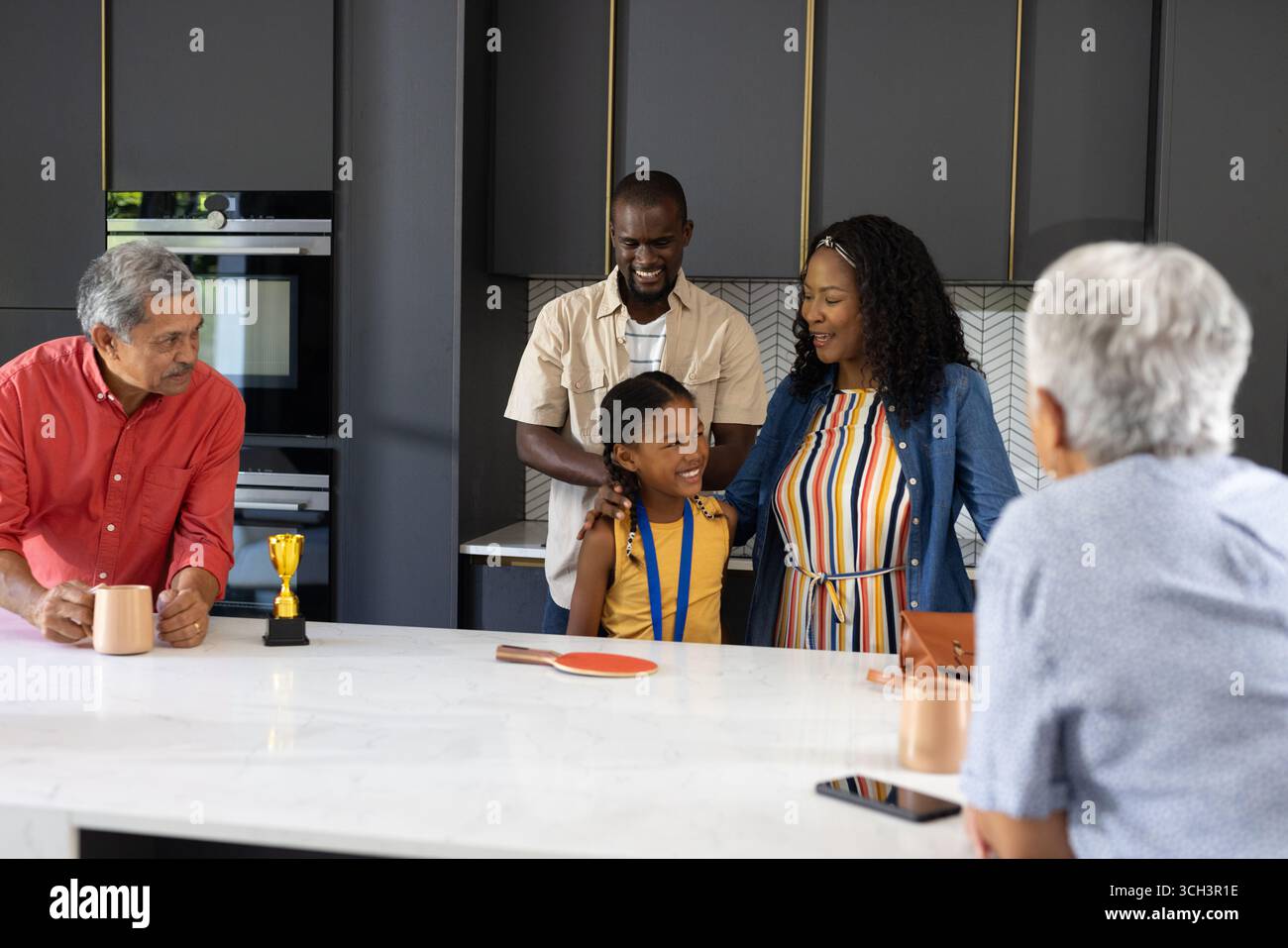 Die Leistung des Kindes feiern, die Familie lächelt zusammen in der Küche und fühlt sich stolz Stockfoto