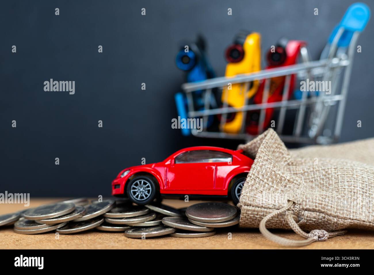 Spielzeugauto kommt aus Sack mit Münzen. Warenkorb mit Autos. Visuelle Metapher für Fahrzeugkosten und Budgetierung. Stockfoto