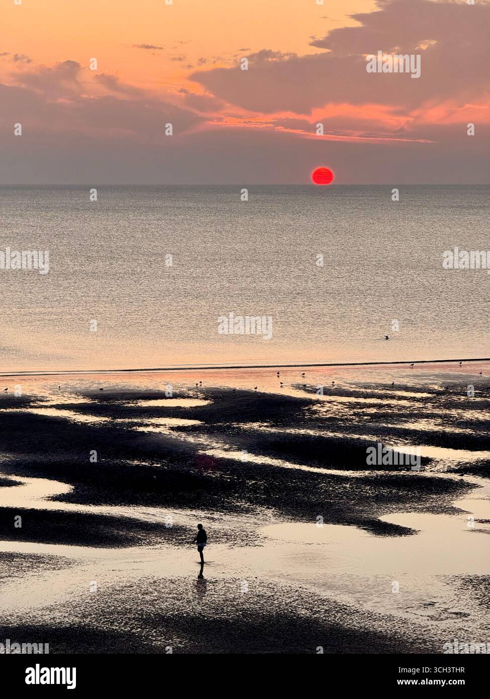 Blackpool Beach bei Sonnenuntergang. Eine Einzelfigur in der Silhouette. Stockfoto