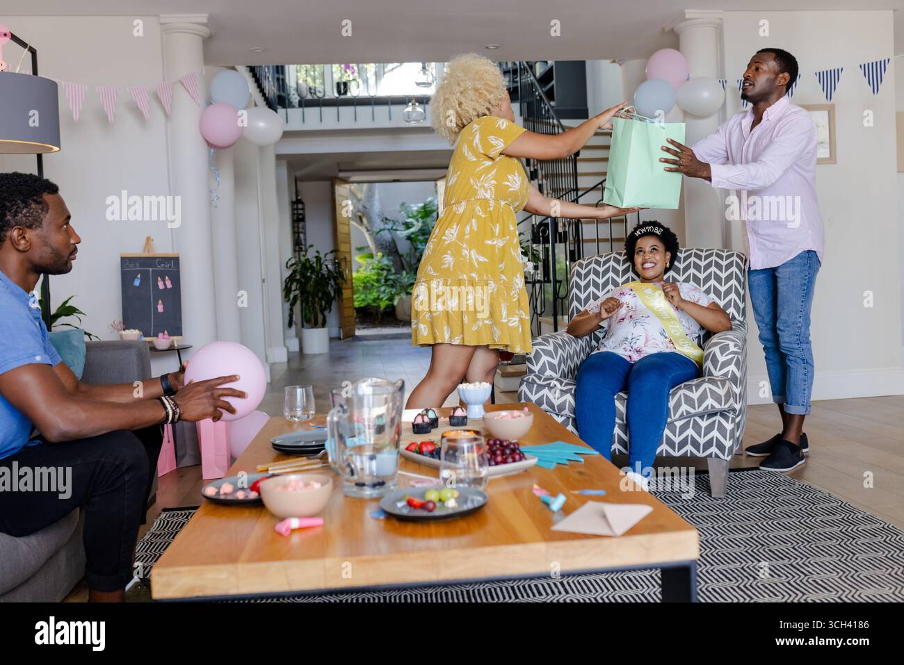 Freunde feiern zu Hause, tauschen Geschenke aus und genießen gemeinsam Snacks Stockfoto