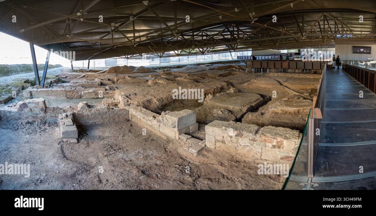 Archäologische Stätte unter einem modernen Dach mit antiken Ruinen und ausgegrabenen Strukturen, mit einem Besucherbereich im Hintergrund von Casa del Anfite Stockfoto