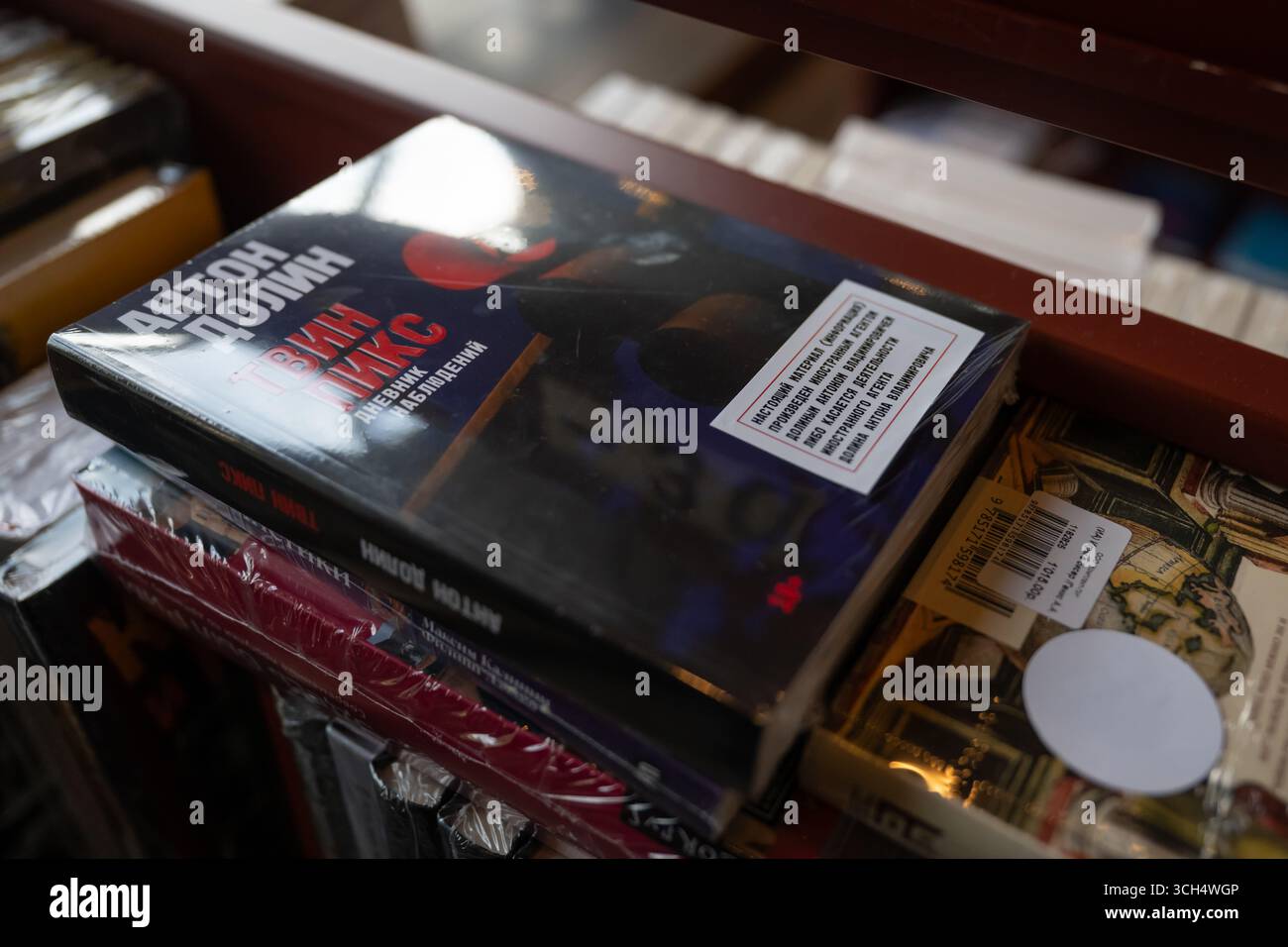 Ein Buch, das mit einem Etikett ausländischer Agenten gekennzeichnet ist, das besagt, dass das Material von einem ausländischen Agenten hergestellt wurde, liegt im Rahmen eines Verkaufs in der Buchhandlung „Podpisnye Izdaniya“ auf einem Regal. Ab dem 1. September 2025 treten in Russland Änderungen der föderalen Gesetzgebung in Kraft, die ausländischen Agenten die Teilnahme an Bildungs- und Aufklärungsaktivitäten verbieten. Obwohl das Gesetz den Verkauf von Büchern durch Autoren mit diesem Status nicht ausdrücklich verbietet, ziehen es Buchhändler vor, auf der Seite der Vorsicht Fehler zu machen und entfernen solche Produkte bereits aus Regalen und Katalogen. Stockfoto