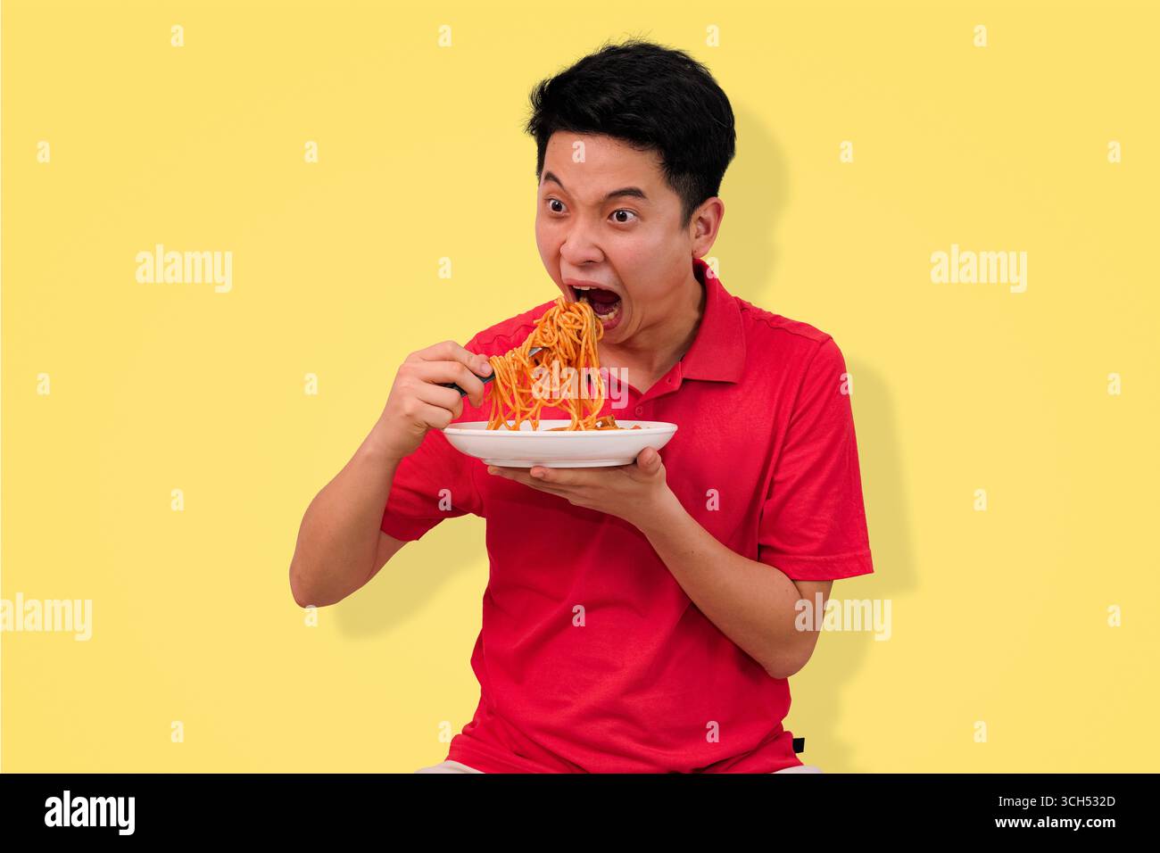 Mann genießt Spaghetti-Mahlzeit mit fröhlichem Ausdruck auf hellgelbem Hintergrund Stockfoto
