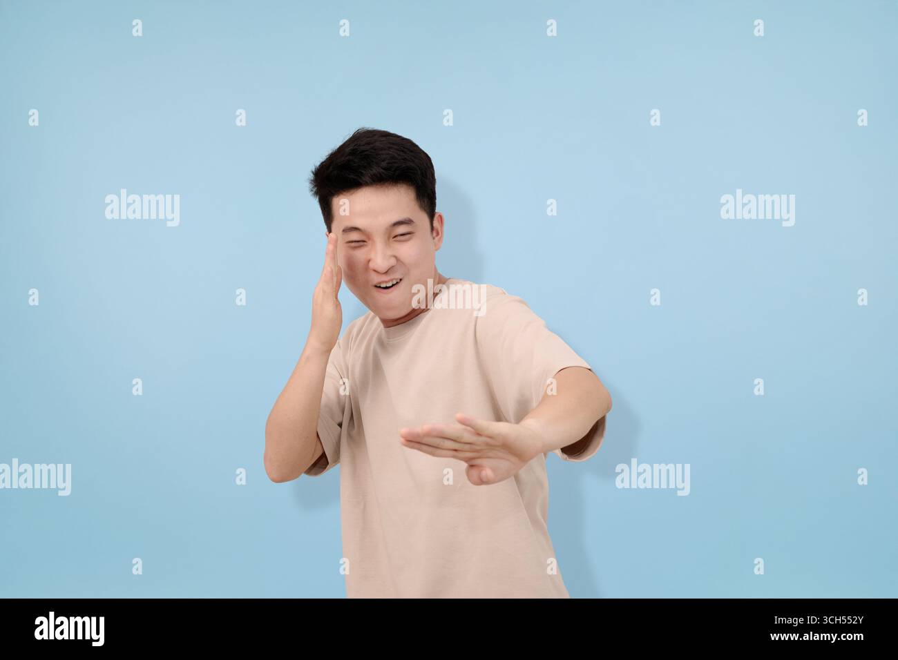 Junger Mann mit Gesten im Studio im blauen Hintergrund Stockfoto