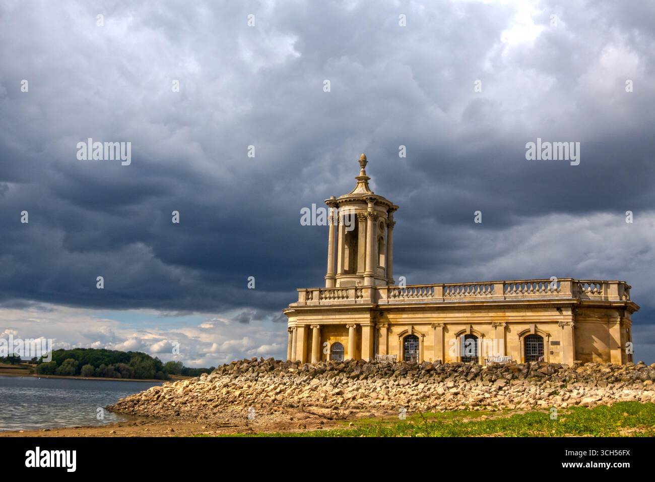 Normanton Kirche von St Mathews mit einem dunklen stürmischen Himmel mit niedrigem Wasser während der Trockenheit am Rutland Water, Anglian Wasserreservoir. August 2025. Stockfoto